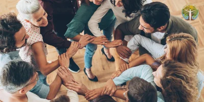 Menschen stehen im Kreis und halten sich an den Händen als Symbol für Gemeinschaft und Vernetzung